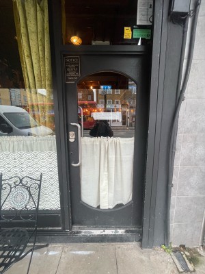Glass door with grey frame ahead. Push silver metal handle on left to open.