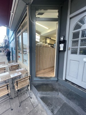 Glass and wooden white door ahead. Push metal handle on left to open.