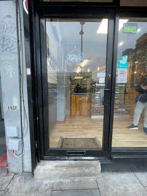 Single glass door with black frame. Pull black handle on left to open.