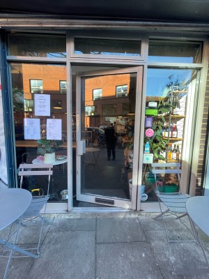 Facing single glass door with metal frame. Push or pull sliver handle on right to open.