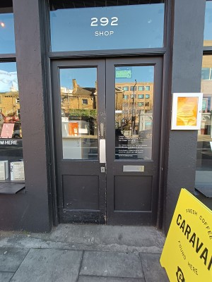Glass door with grey wooden frame. Push from middle to open.