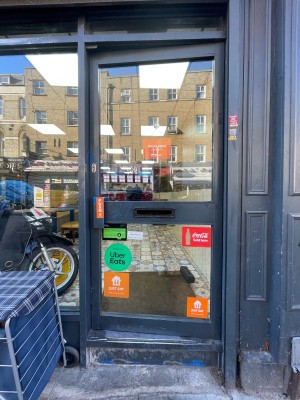 Single glass door with black frame. Push handle on left to open.