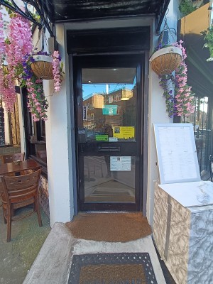 Glass door with black, metal frame. Push black metal handle on left to open.