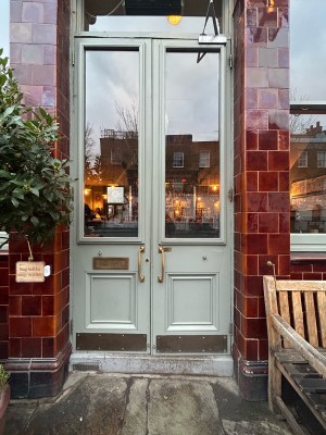 Light green wooden doors with glass panels ahead. Pull gold metal handles in centre to open.