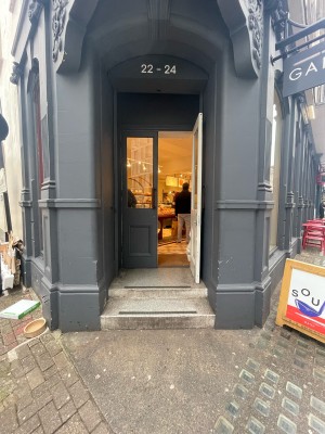 Glass and wooden grey doors ahead. Pull metal handles in centre to open. Two steps up before doors.
