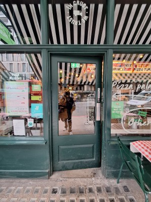 Glass door with green frames ahead. Push on right to open.