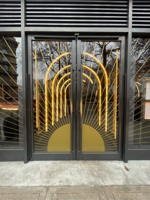 Glass doors with black metal frame. Push from metal handles in centre to open.
