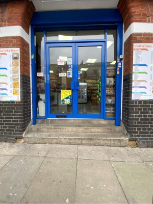 3 steps up followed by glass doors with blue frames ahead. Push from handles in centre to open.