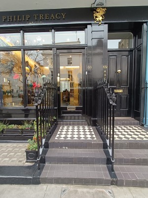 From street, facing venue. Path to entrance ahead. Three steps up. Black, metal railings with spikes along left and right of path.