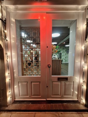 One step up to glass doors with white frames. Push in centre to open.