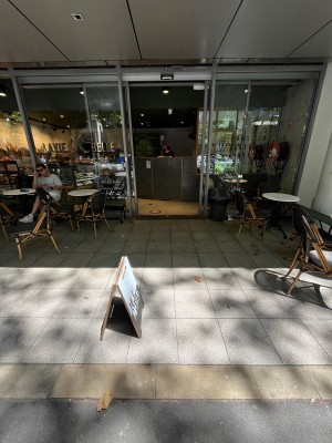 Path to entrance through outdoor front seating. A-frame sign obstructing.