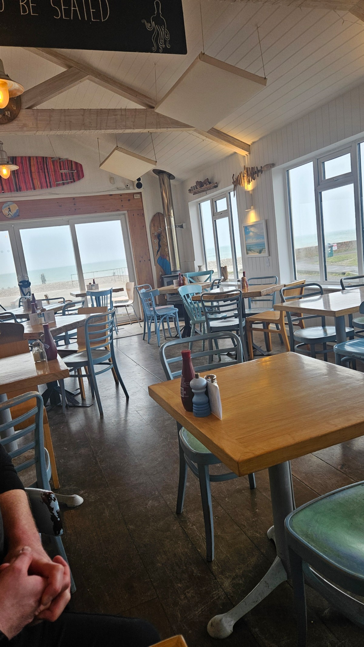 A view of the cafe with lots of tables and chairs. Windows surrounding all sides