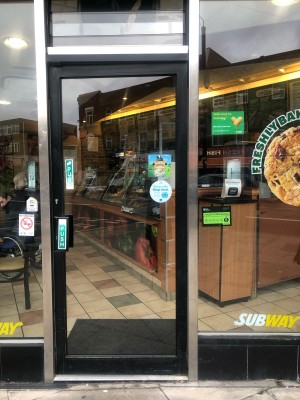 Glass door with black frame. Push handle on left to open.