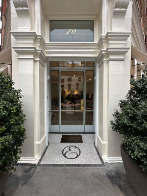 White wooden door ahead. Push bronze handles from centre to open. Trees to either side.
