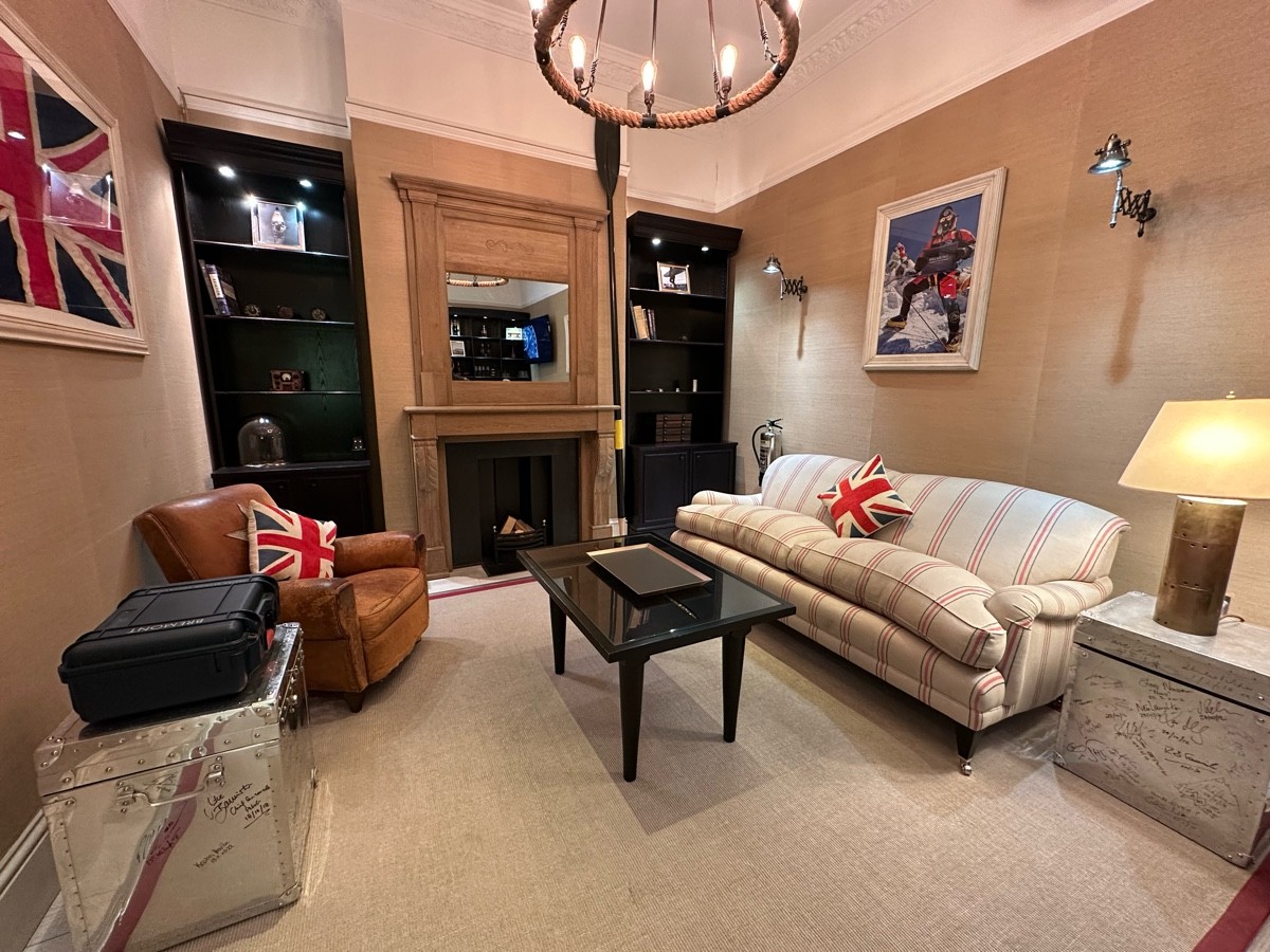 From opening facing straight. Couch, armchairs and low table ahead. Fireplace at back.