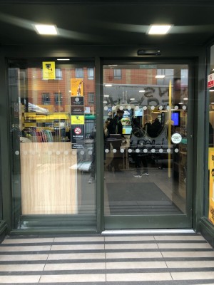 Glass door with grey frame. Slides from right to open.