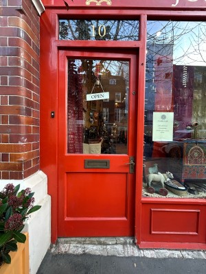 Red wooden door with large glass panel ahead. Push gold handle on right to open.