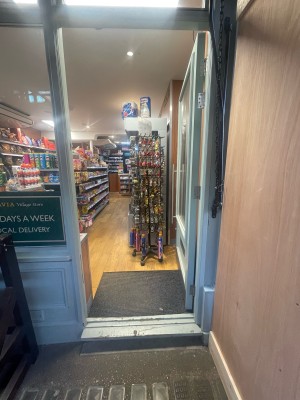 Glass door with blue frame ahead. Push silver metal handle on left to open.