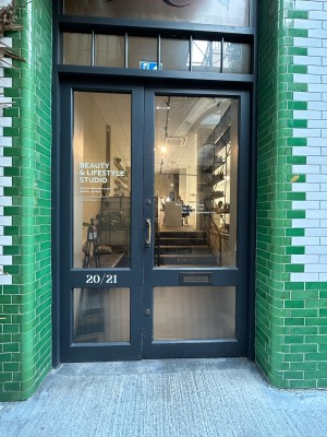 Glass door ahead with black frame. Push gold handle in centre to open.