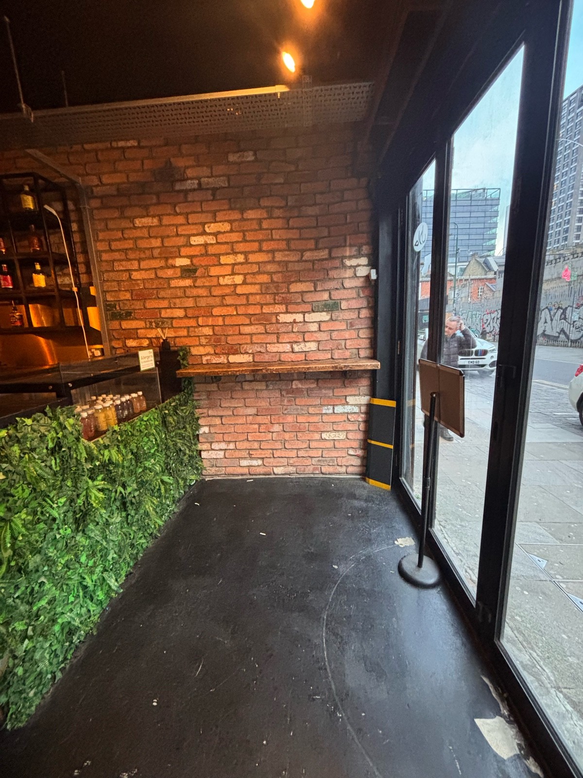 From entrance facing right. Bar along left. Standing height table along back. Waiting area ahead.