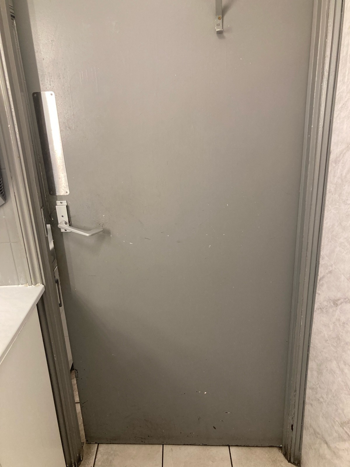 Back of door ahead. Grey door with handle on left.