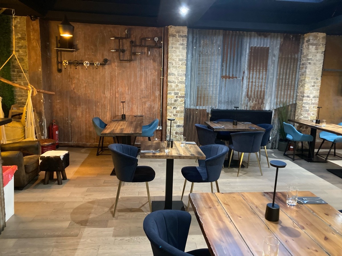 From end of path facing left. Tables and chairs ahead and along right. Armchair on back left.