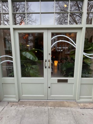 Glass doors with grey wooden frame. Push from gold handles at centre to open.