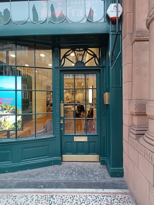Glass door with green frame. Push from left to open.