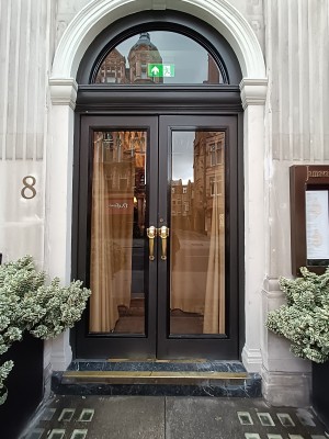 Glass door with black frame. Pull from golden handle at centre to open.