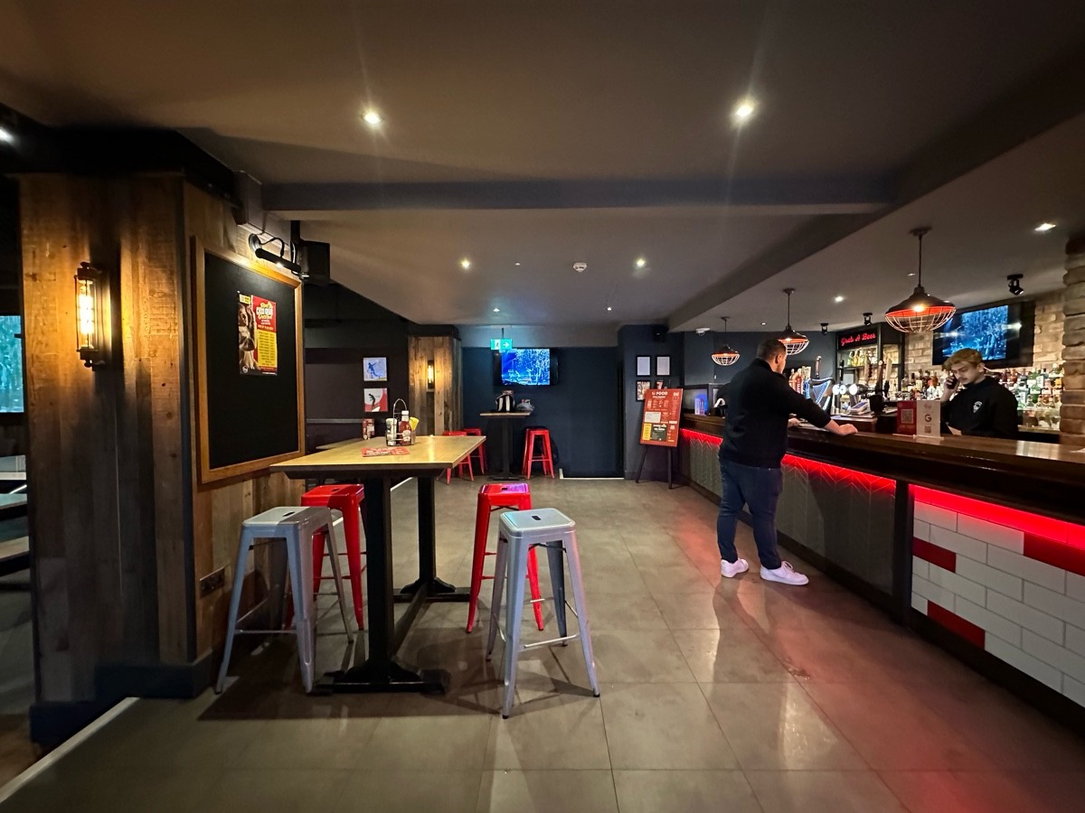 From entrance facing right. Bar along right. High tables and stools along left. Opening behind.