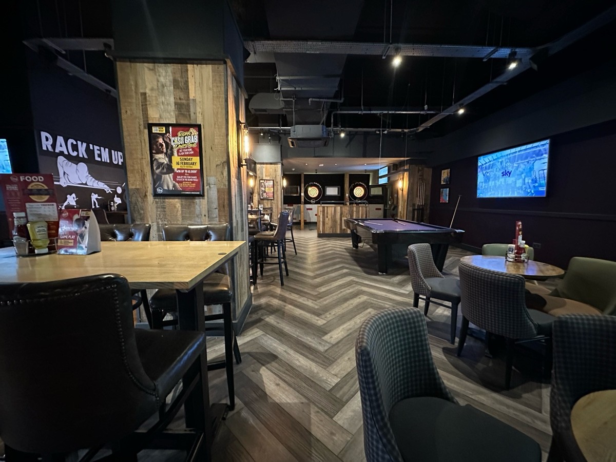 From after high table facing left. High tables, stools and pillars along left. Tables and chairs to right. Pool table behind.