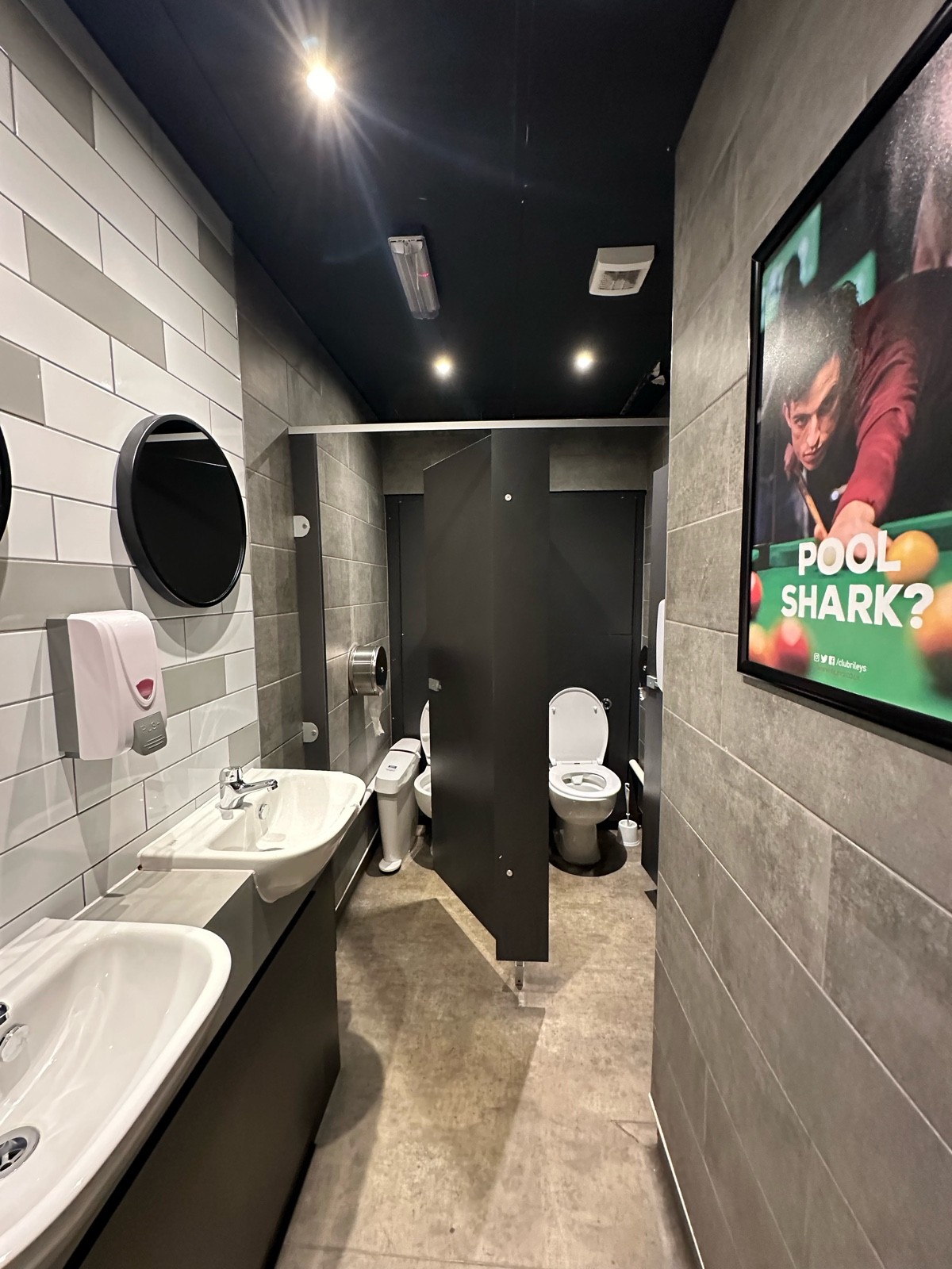 From door facing left. Sinks along left. Cubicles along back.