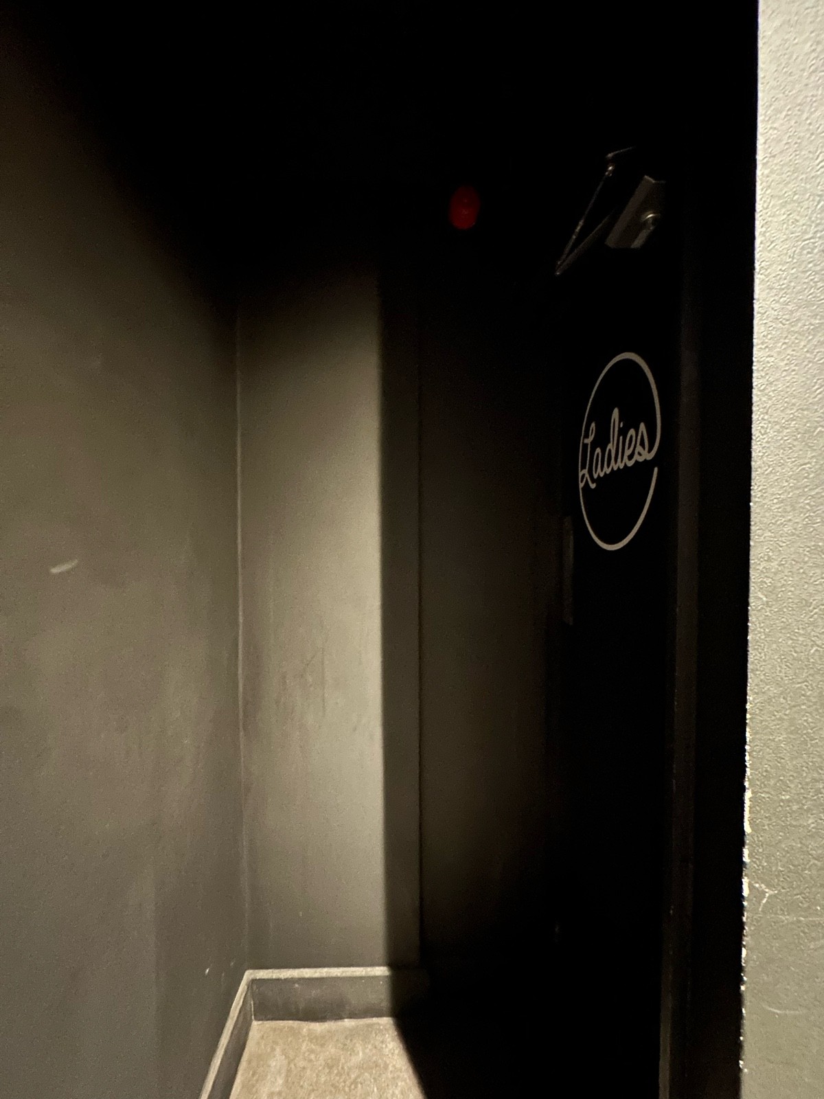 From door facing straight. Second preceding door to women’s bathroom ahead to right.