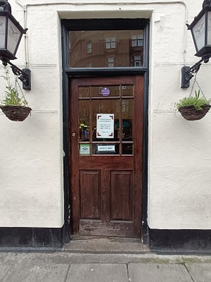 Glass door with brown, wooden frame. Push from left to open.
