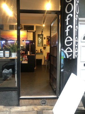 Glass door with black frame. Push handle on left to open.
