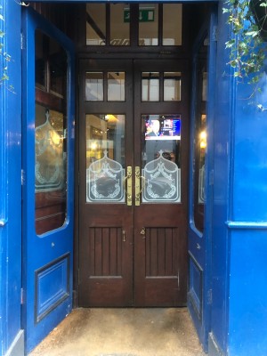 Glass doors with blue frame. Push from centre to open.