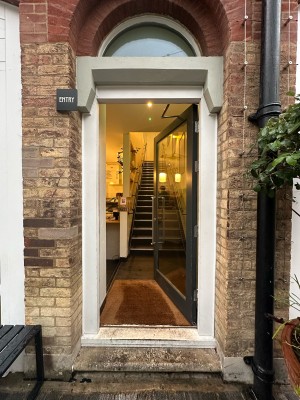 Glass door with black and white frame. Push handle from left to open.