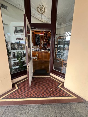 Glass door with brown wooden frame and gold handle on right. Pull to open.