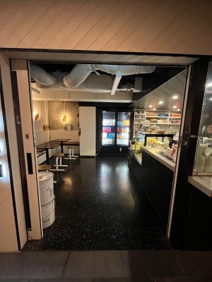 Glass door with white metal frame and black handle on right. Door slides open to left.