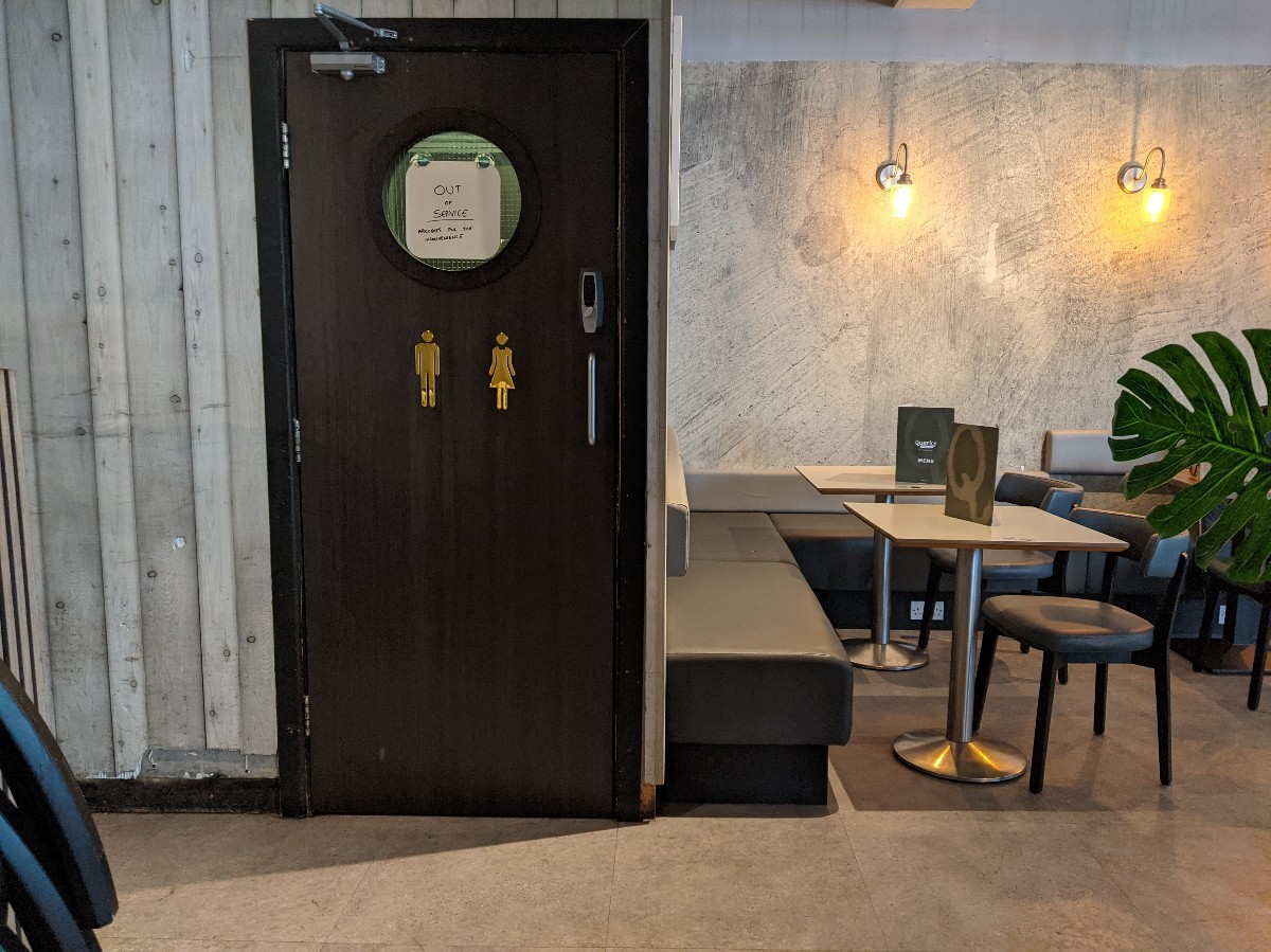 From end of ramp facing left. Door to toilet ahead left. Half booths with chairs ahead right.