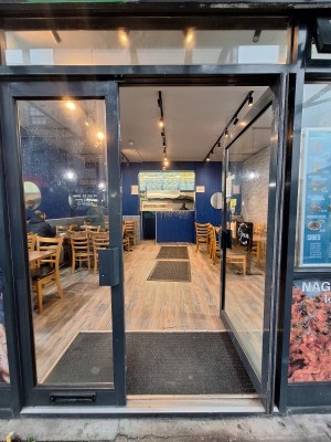 Glass doors with black frames ahead. Push in centre to open.