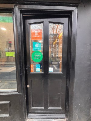 Black glass paneled door ahead. Push metal handle at center left to open.
