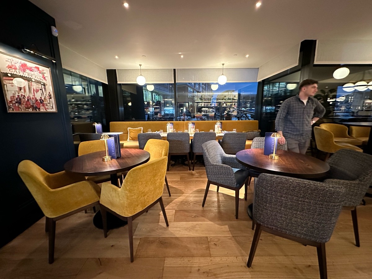 From archway facing left. Tables and chairs ahead. Half booths behind.
