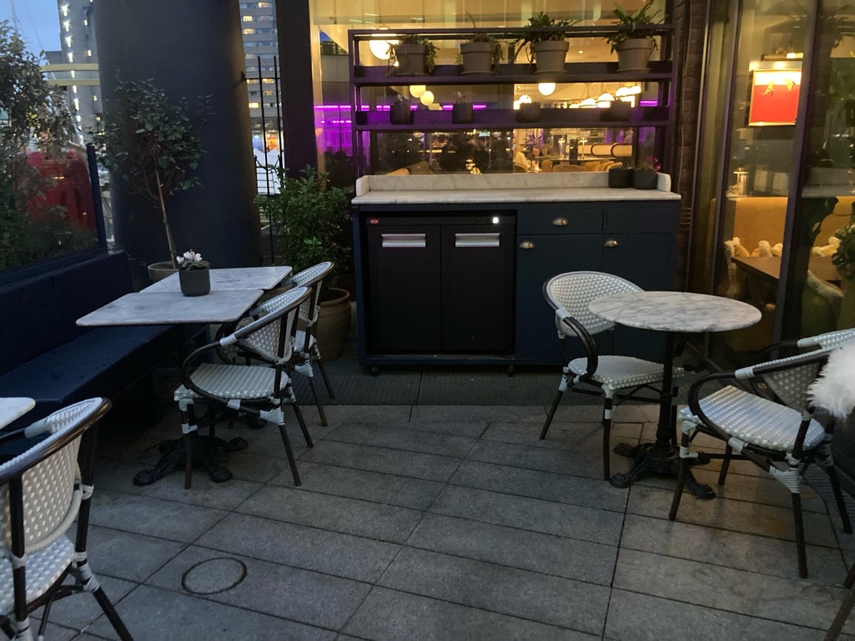 From end of path facing right. Half booth along left. Staff desk on back. Tables and chairs on right.
