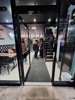 Glass door with black frames. Push on right to open.