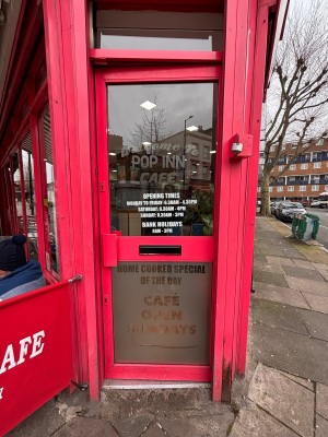 Glass door with red frame ahead. Push metal handle at center left to open.