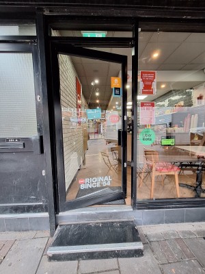 Glass door with black frames. Push black handle on right to open.