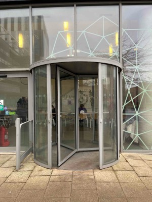 Main entrance of the cafe. Revolving glass door. Requires manual push. Entrance and cafe is on the ground floor.