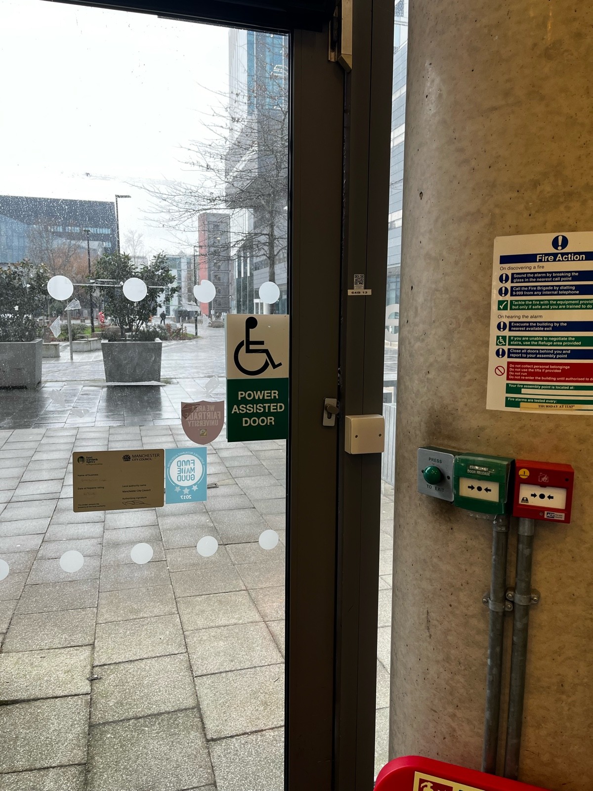 Door from inside of cafe. “Press to exit” button is located to the right of the door. Button is big, round, and green.