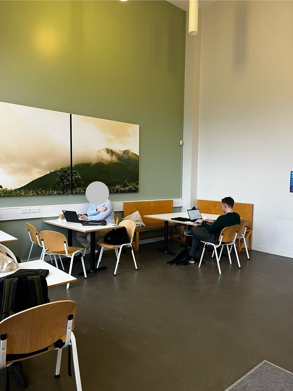 Left side of cafe from standing at the entrance. Tables with chairs and/or benches are available. One large table can accommodate 6 people.